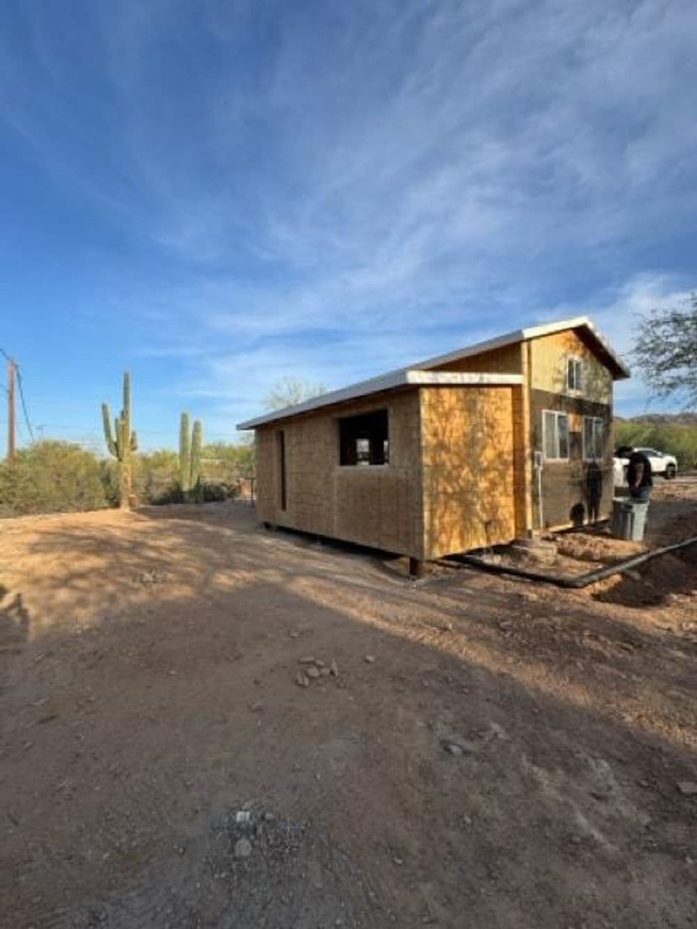 Desert house under construction with cacti and blue sky in the background.