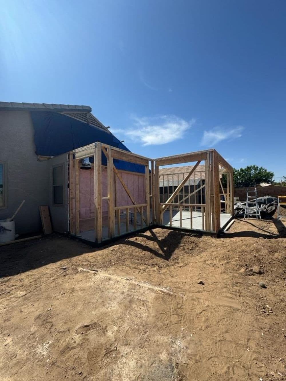 Construction site featuring framed structures for home additions on a clear day.