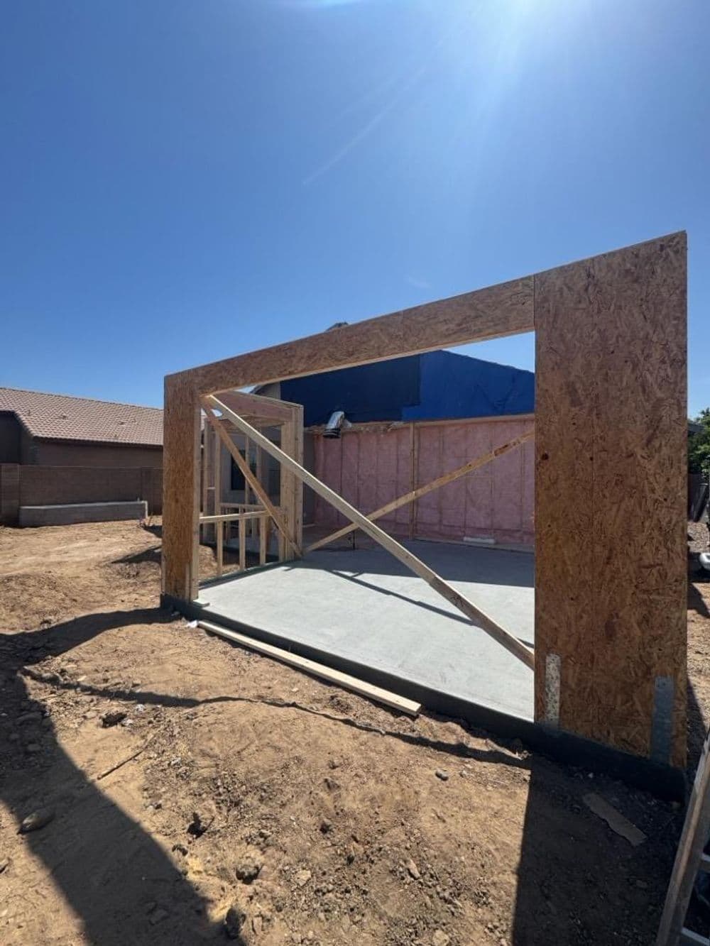New home construction featuring wooden frame and foundation in a sunny outdoor setting.