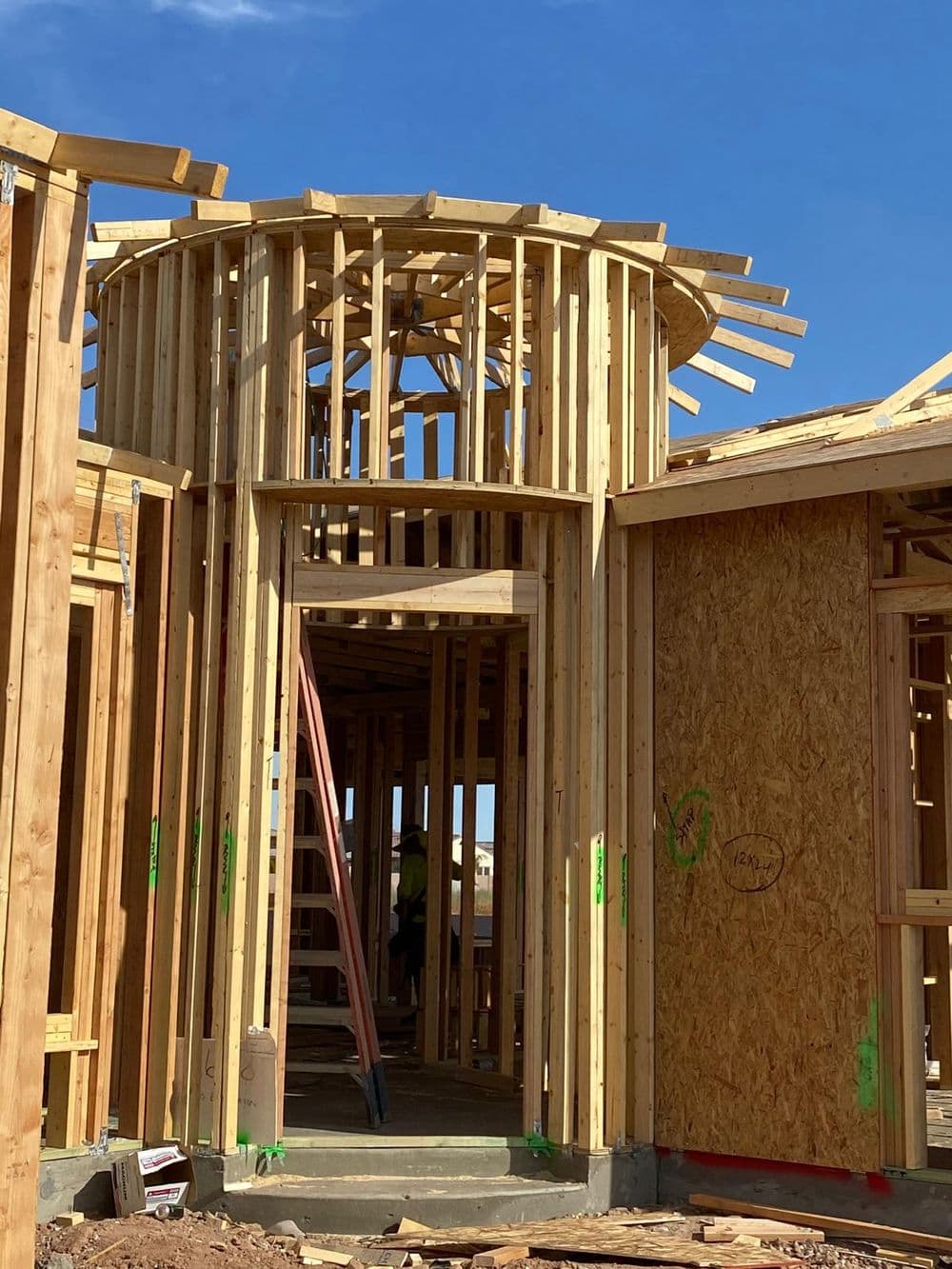 New construction home frame with wooden structure, beams, and clear blue sky.
