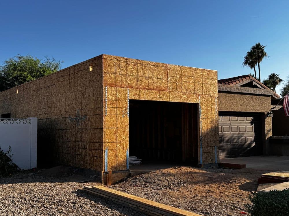 New wooden structure under construction with an open garage in a residential area.