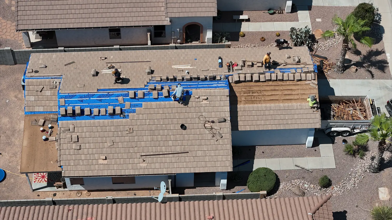 A whole house roof mid-replacement from above, shingle bundles staged across the deck