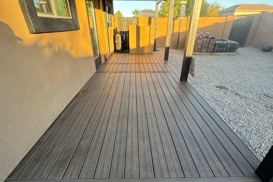 A finished composite deck running the length of a house under a covered patio