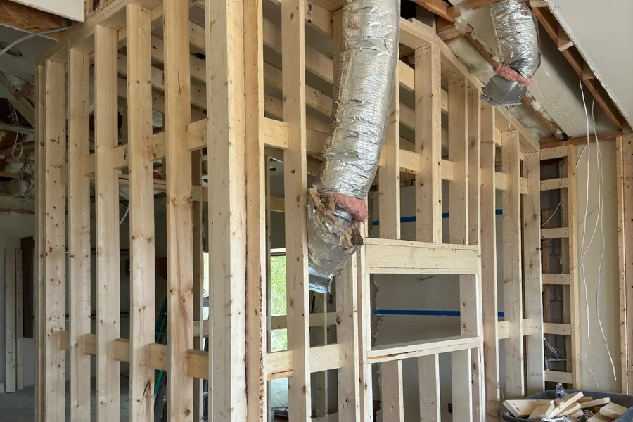 A house interior taken back to the studs, with new partition framing and ductwork in