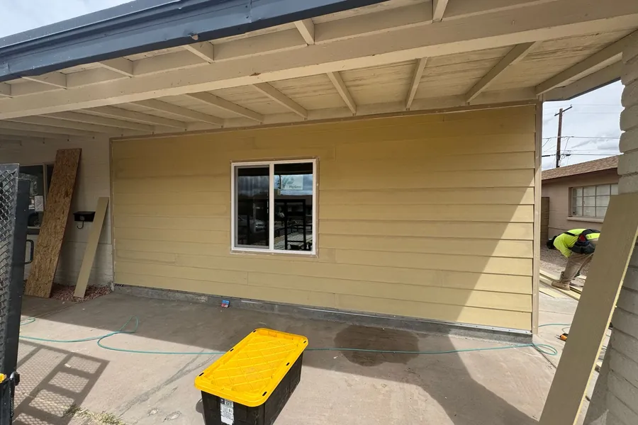 New lap siding and a new window on a house wall under exposed rafter tails