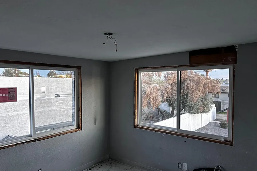 A stripped room with two new windows fitted, waiting on trim and paint