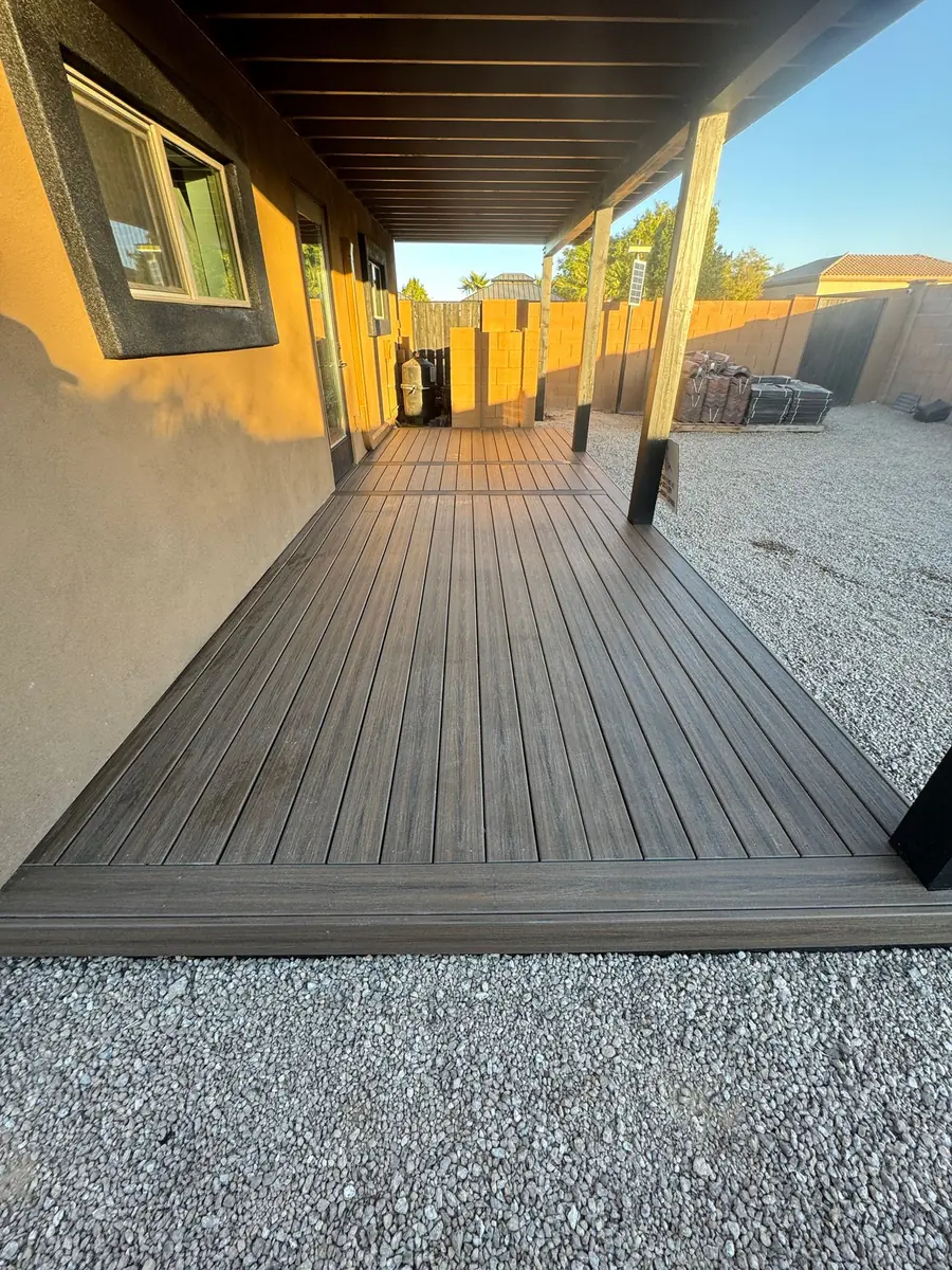 A finished composite deck running the length of a house under a covered patio