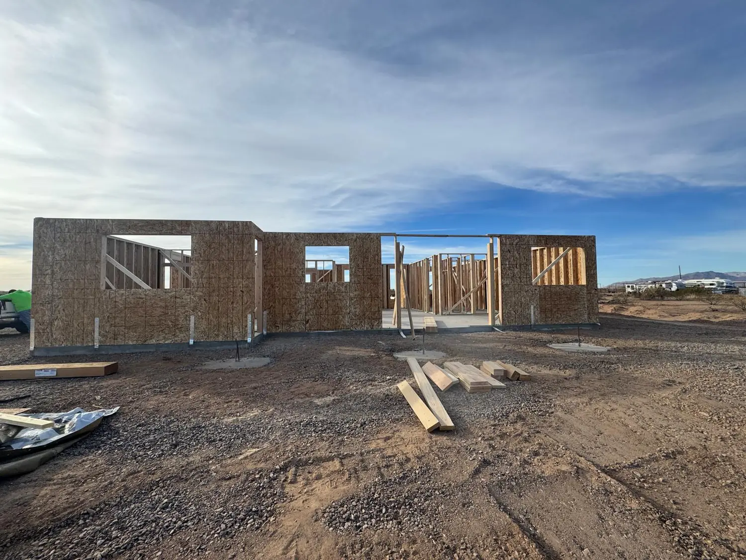Sheathed exterior walls standing across the footprint of a house on an open desert lot