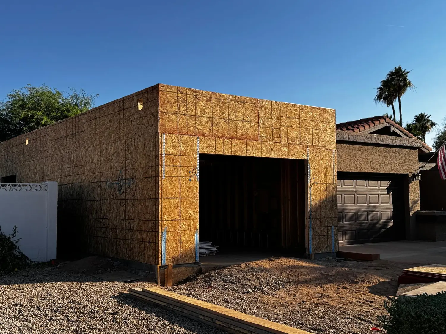A sheathed garage addition beside an existing house in the late afternoon