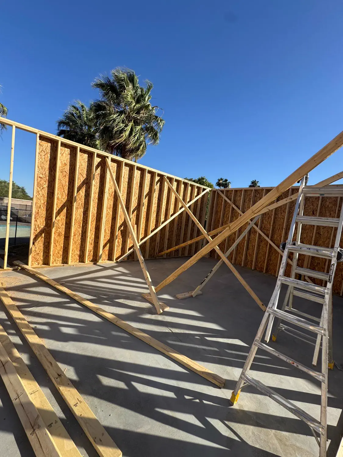 A framed wall and stepladder partway through a framing day