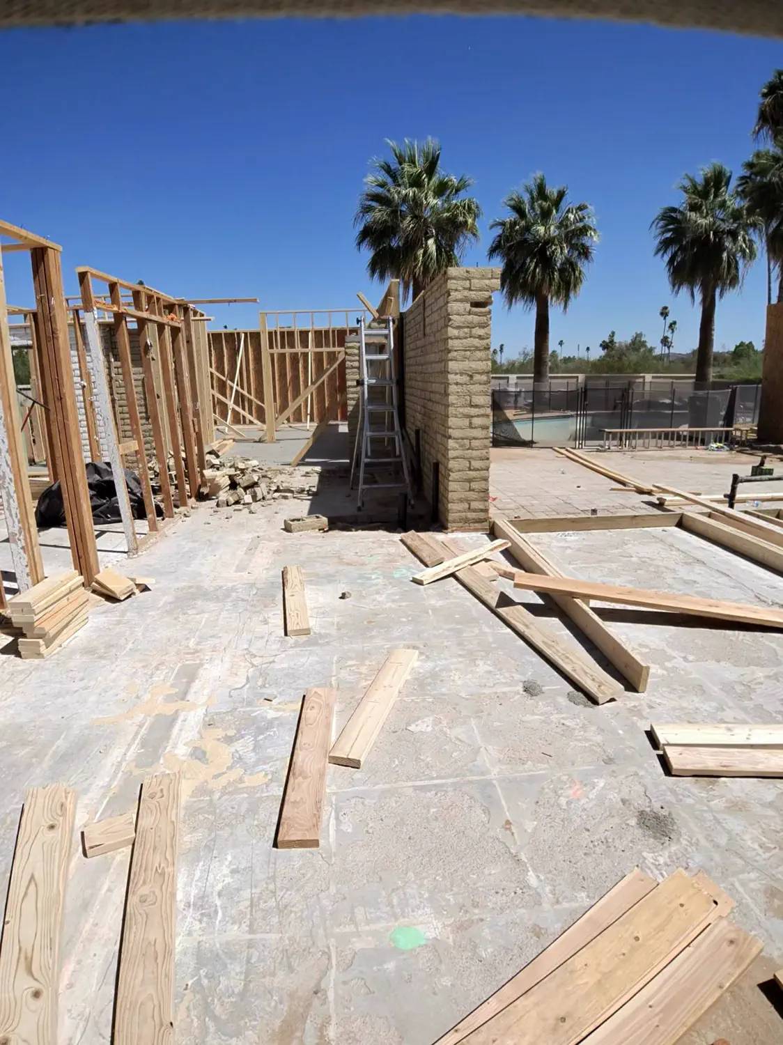 Framing lumber stacked on the slab beside finished walls