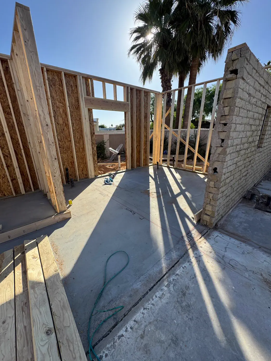 Framed walls rising between the palms on an Arizona lot