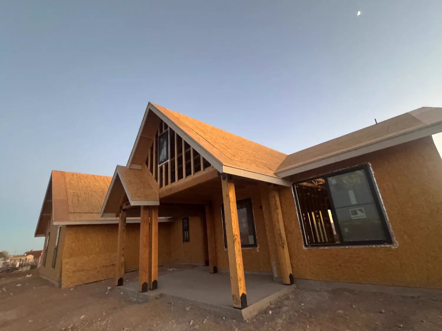 A Quest Construction custom home at dusk with the porch framing complete