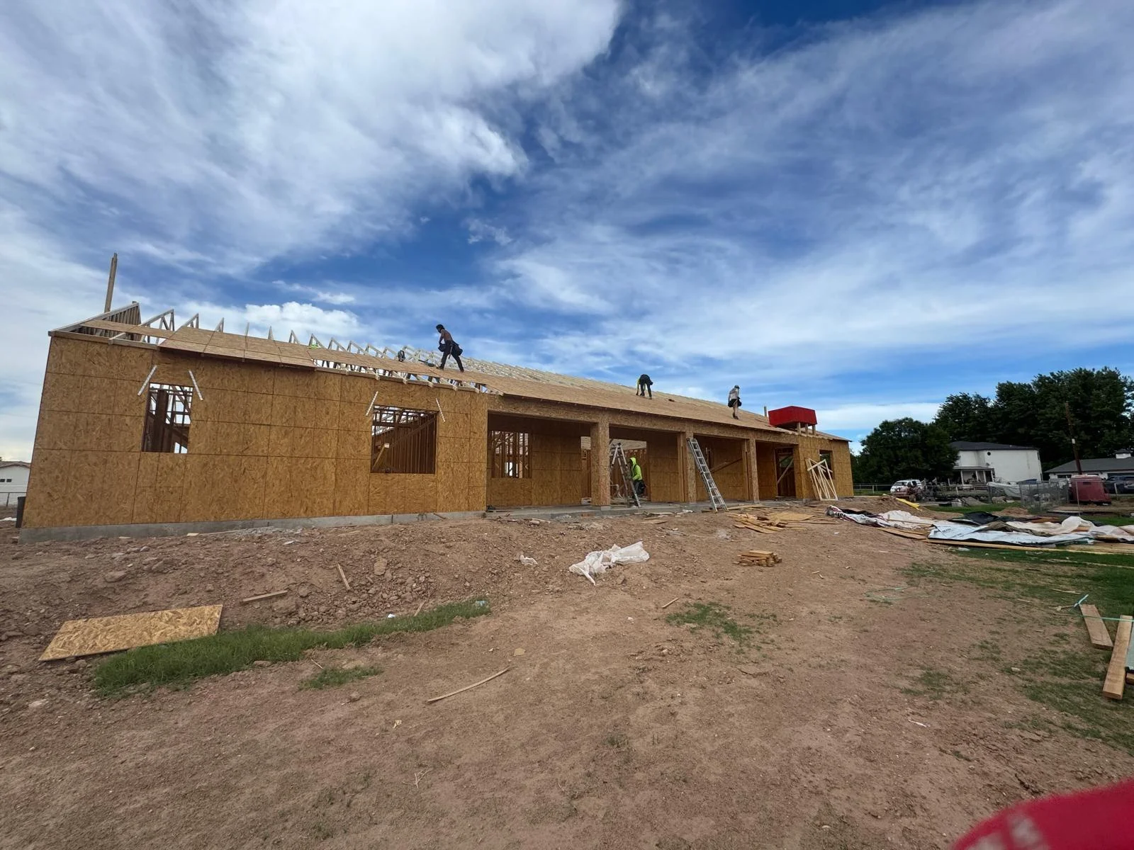 Wide exterior view of a sheathed house at a build site