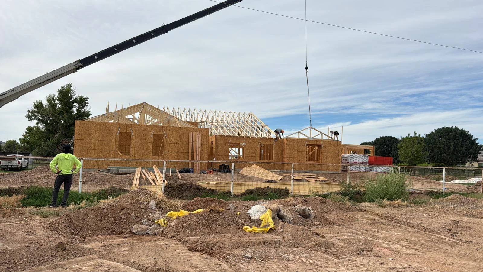 A crane lifting roof framing over a house under construction