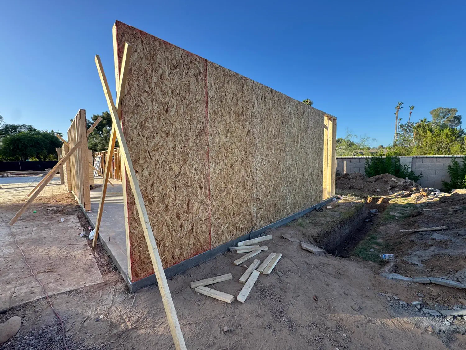 A sheathed exterior wall panel braced upright on a new slab