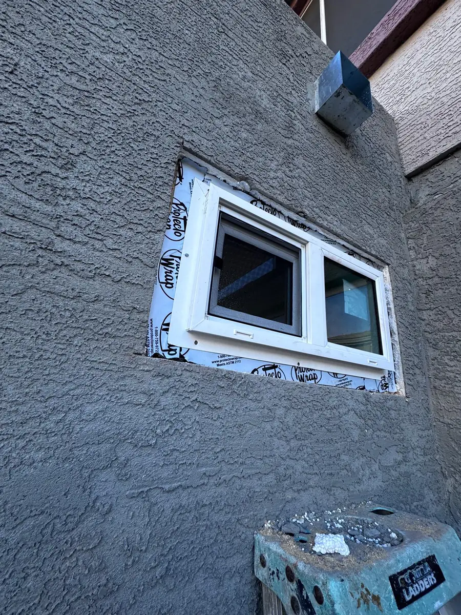 A new window flashed into a stucco wall with the sealing tape still exposed