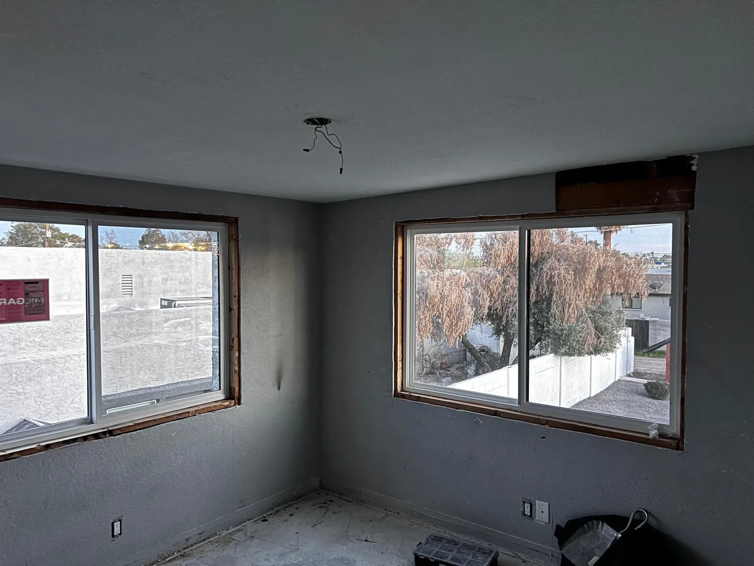 A stripped room with two new windows fitted, waiting on trim and paint
