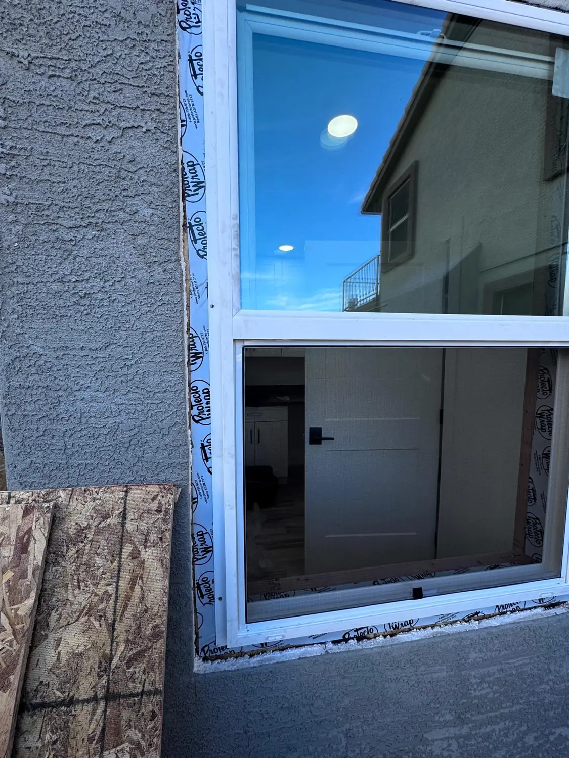 A new window fitted into its opening, the sky reflected in the upper light