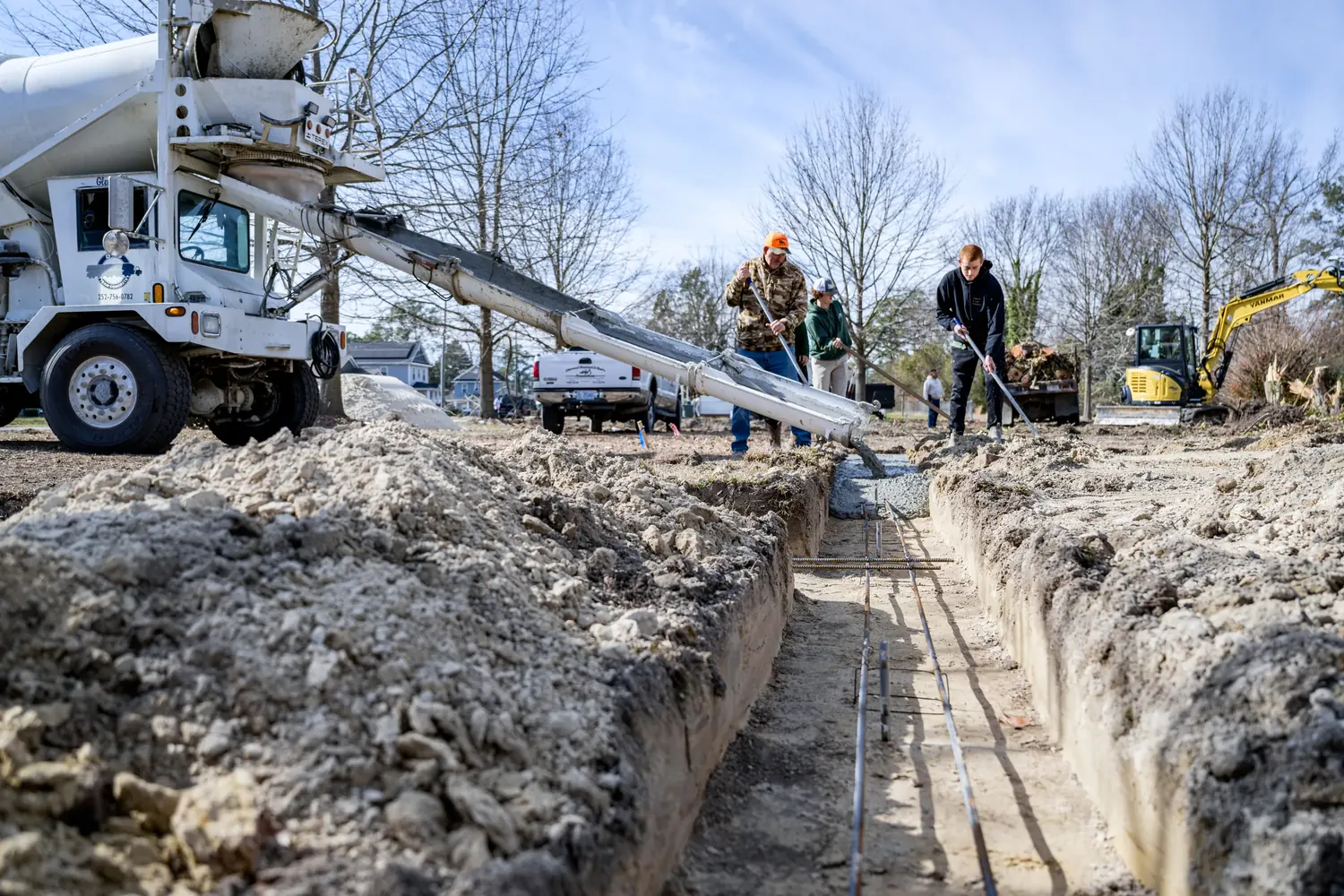 Concrete being placed for a slab beside a framed house