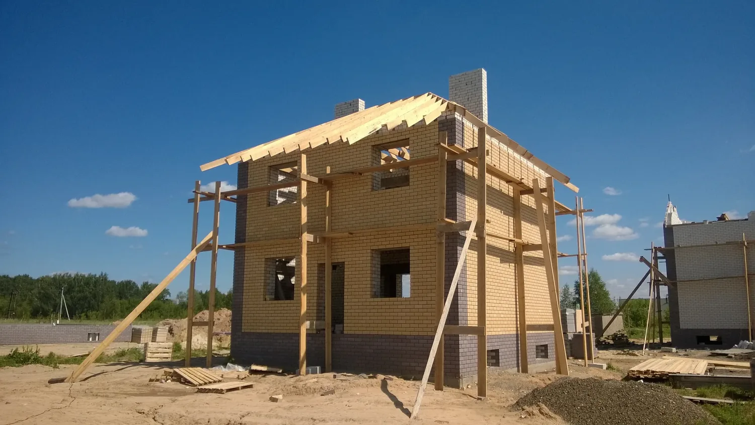 The framed shell of a house under a clear sky