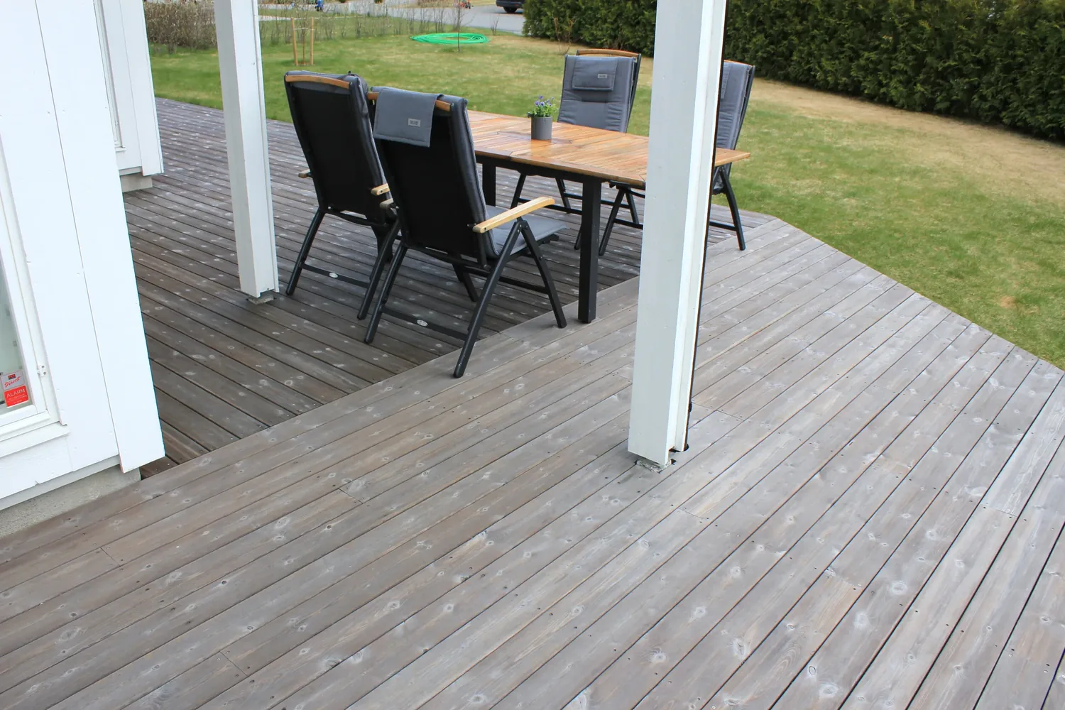 A timber deck set out with a table under a covered roof