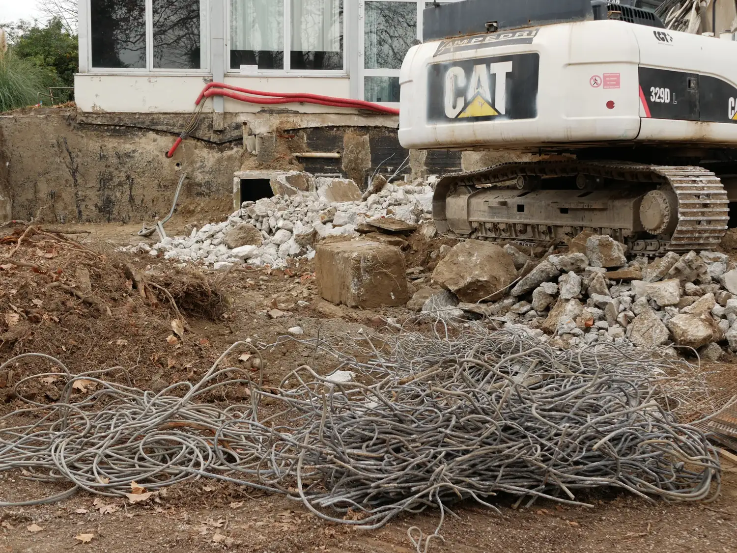 A tracked excavator standing in the rubble of a demolished building