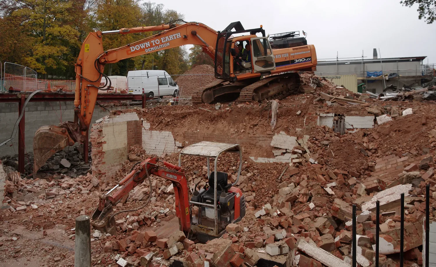 An excavator loading demolition debris out to a cleared site