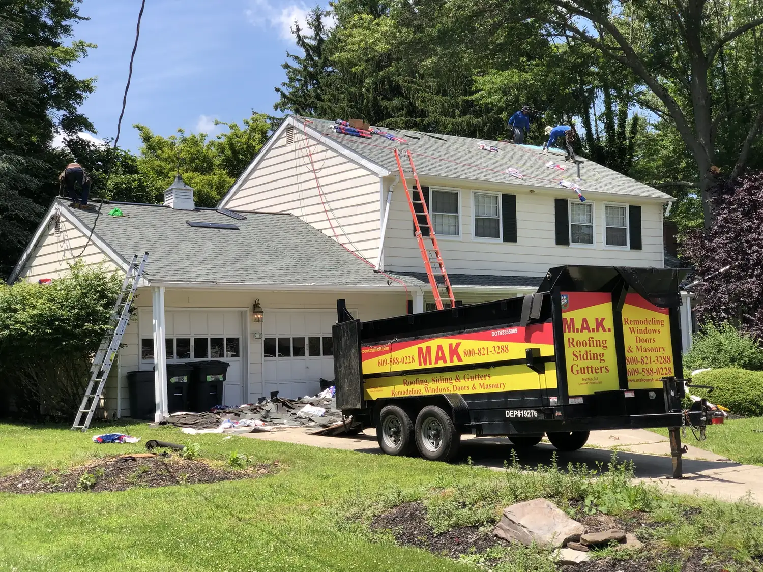 A tear-off truck pulled up to a house with the roof being stripped
